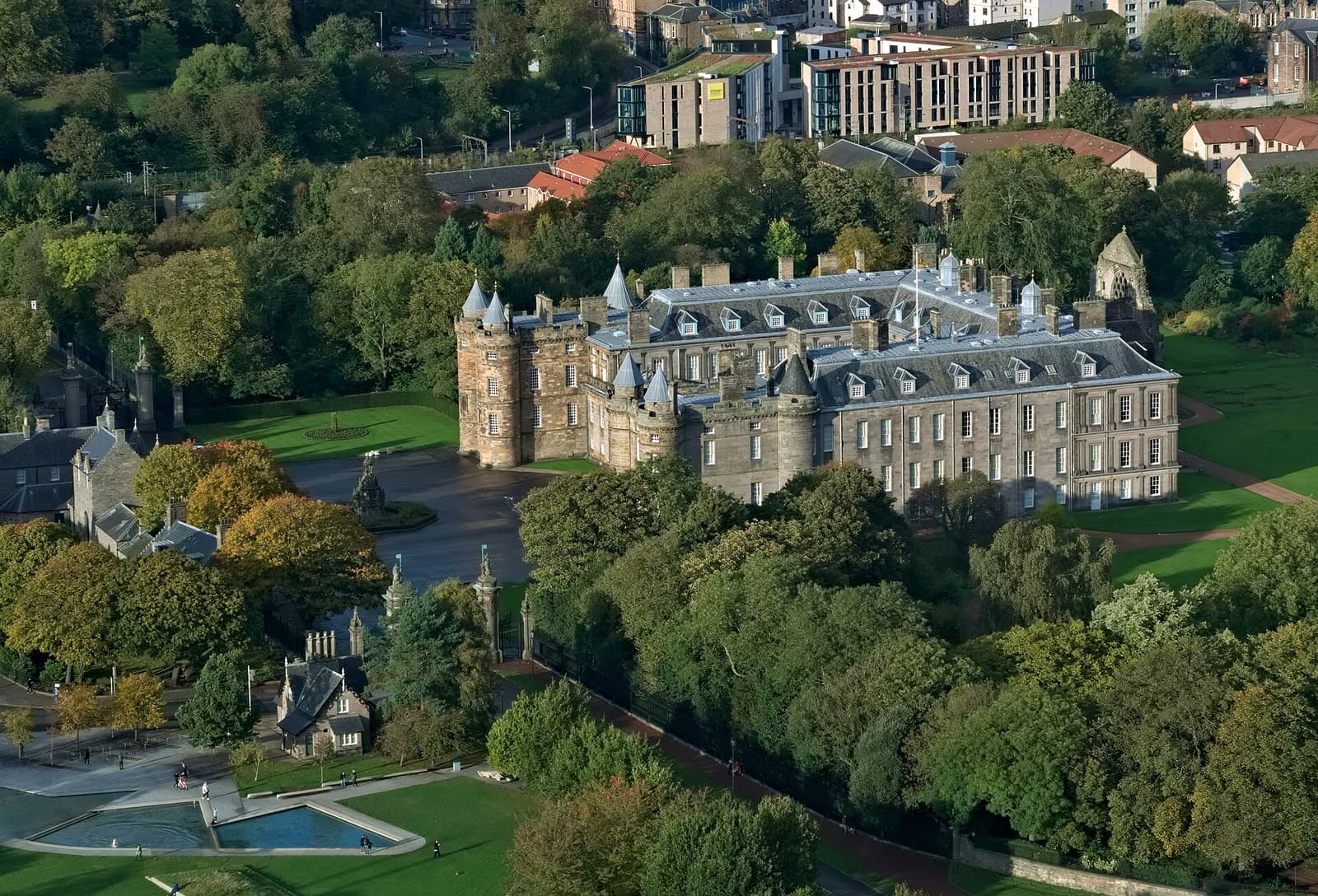 The Palace of Holyroodhouse among trees, seen from Salisbury Crags above Holyrood Park