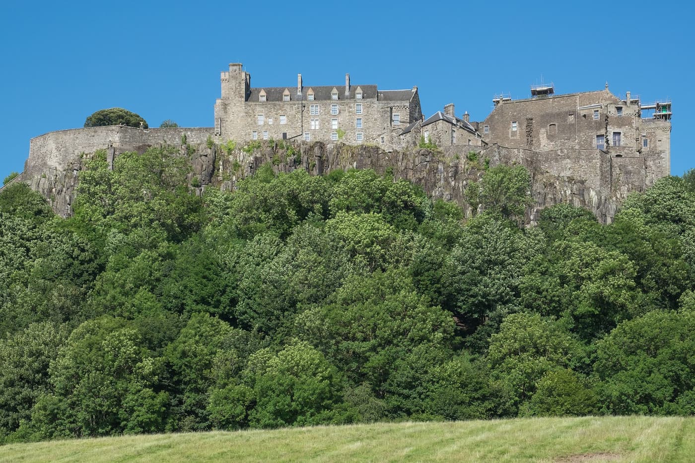 Stirling Castle on its wooded crag above a green field