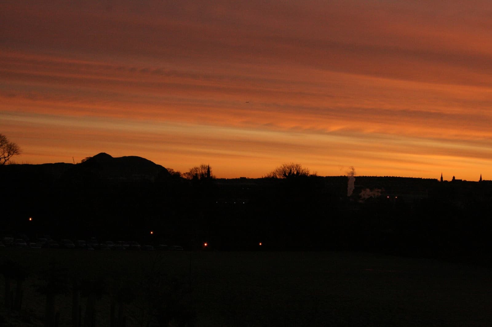 The dark outline of Arthur’s Seat against an orange dawn sky