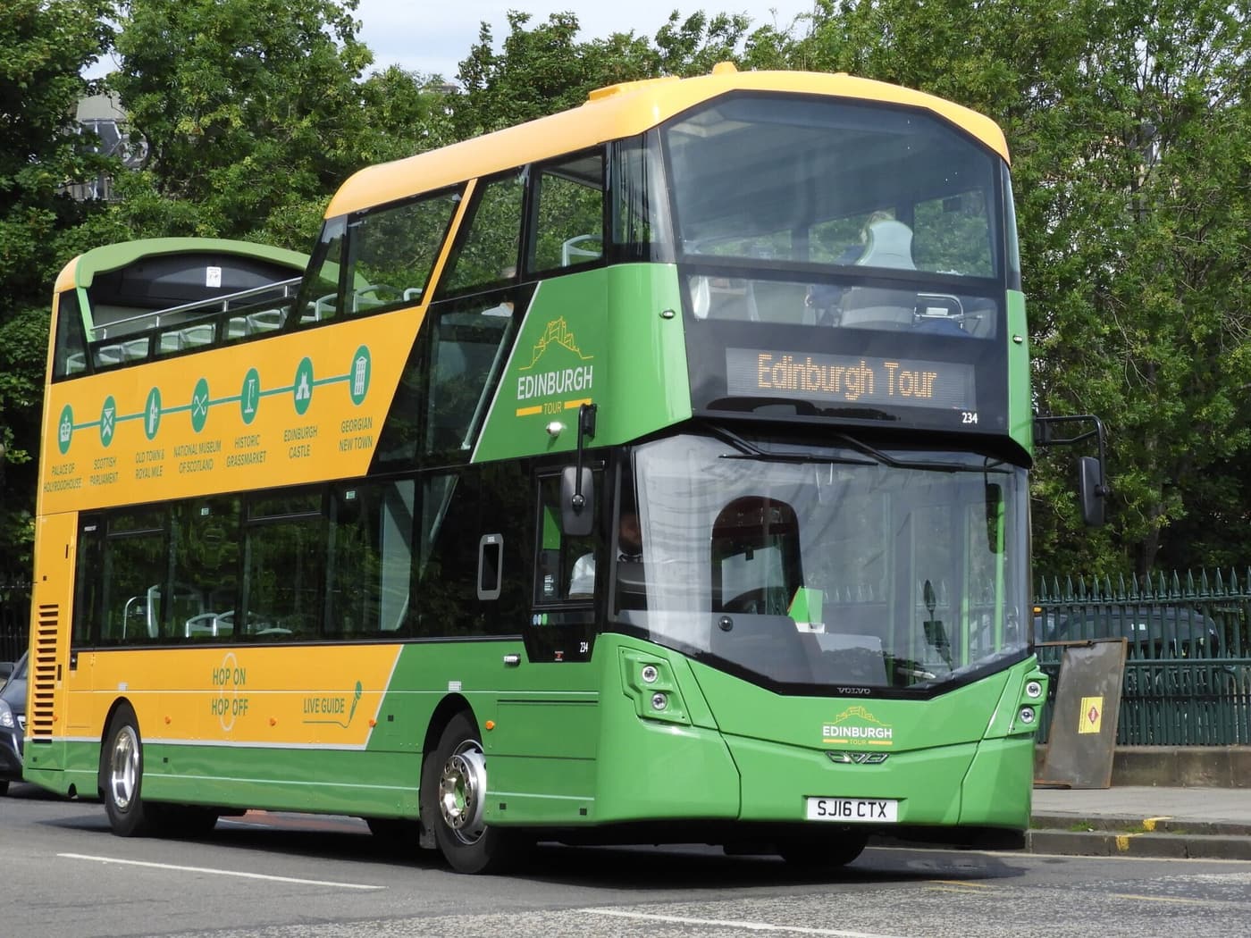 A green and yellow open-top Edinburgh Tour double-decker bus